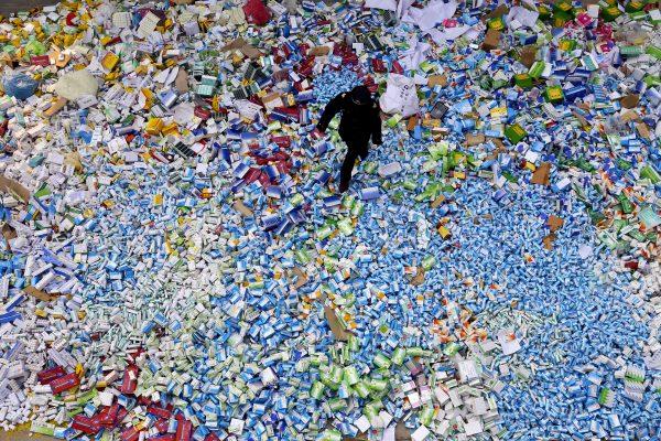 This picture taken on March 14 shows a Chinese policeman walking across a pile of fake medicines seized in Beijing. (STR/AFP/Getty Images)