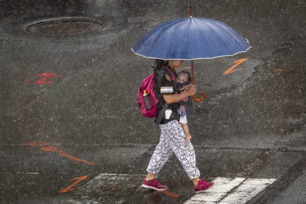 A young woman walks with child underneath her umbrella during a heavy rain in Philadelphia, Monday, Aug. 13, 2018. (Alejandro A. Alvarez/The Philadelphia Inquirer/AP)