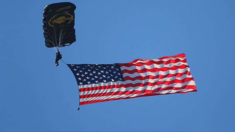 The flag is the most popular and potent symbol of America—it should be treated with care. Here a member of the U.S. Army Jump Team displays the flag while descending over Sebring International Speedway before a race. (Chris Jasurek/ The Epoch Times)