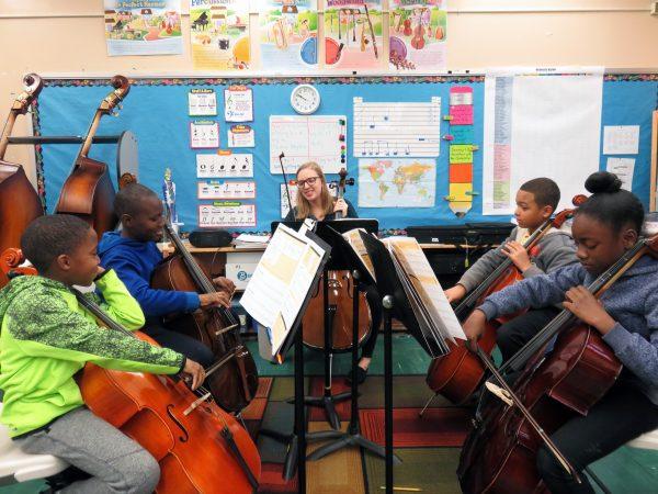 Grade school students learning to play the cello at a school partnering with ETM. (Education Through Music)