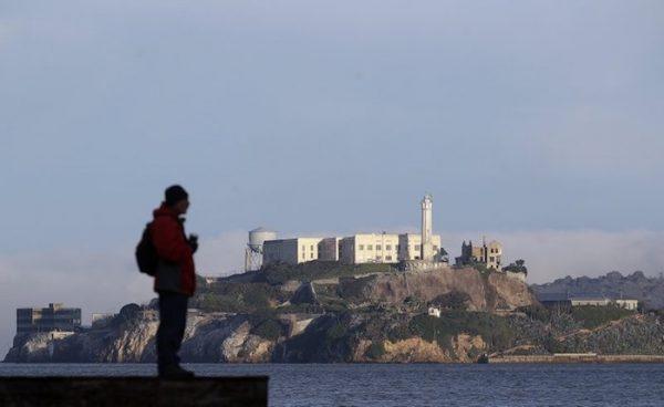 A man stands on a pier with Alcatraz Island at rear in San Francisco, on Dec. 22, 2018. (AP Photo/Jeff Chiu)