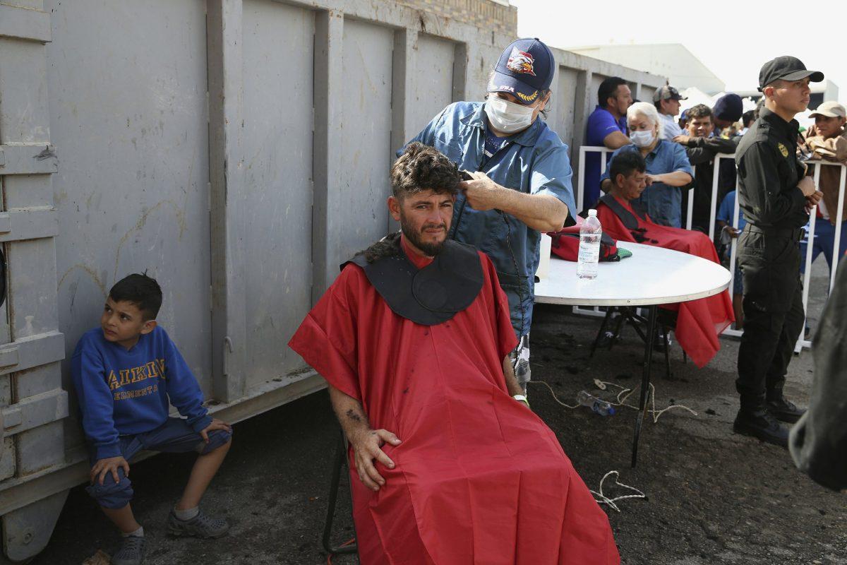 A Central American immigrant gets a haircut at a shelter in Piedras Negras, Mexico, Feb. 5, 2019. (Jerry Lara/The San Antonio Express-News via AP)
