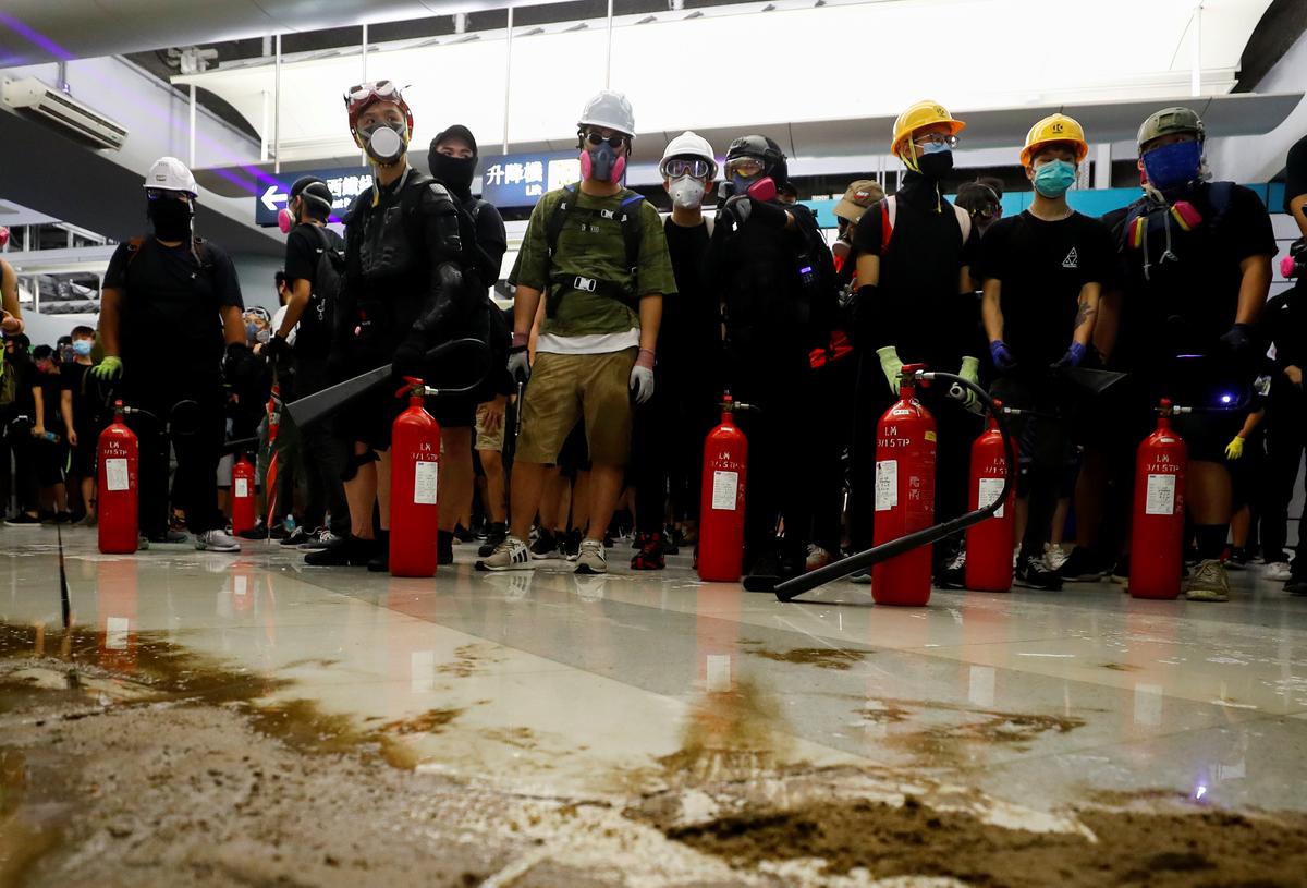 Protesters gather after firing nitrogen extinguishers towards the riot police during a stand off at Yuen Long MTR station, the scene of an attack by suspected triad gang members a month ago, in Yuen Long, New Territories, Hong Kong, China on Aug. 21, 2019. (Kai Pfaffenbach/Reuters)