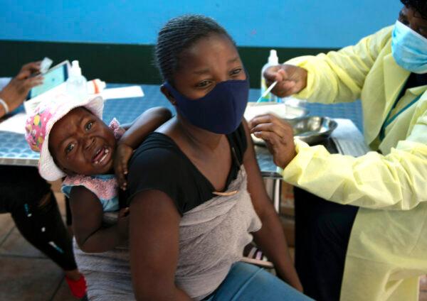 A mother receives her Pfizer vaccine against COVID-19 in Diepsloot Township near Johannesburg, Oct. 21, 2021. (AP Photo/Denis Farrell)