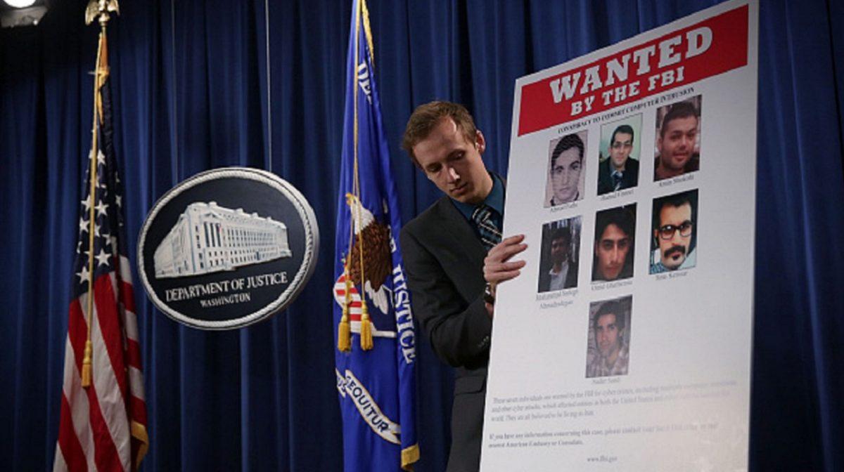 A Department of Justice employee put up a poster of the seven indicted hackers prior to a news conference for announcing a law enforcement action in Washington on March 24, 2016. (Alex Wong/Getty Images)