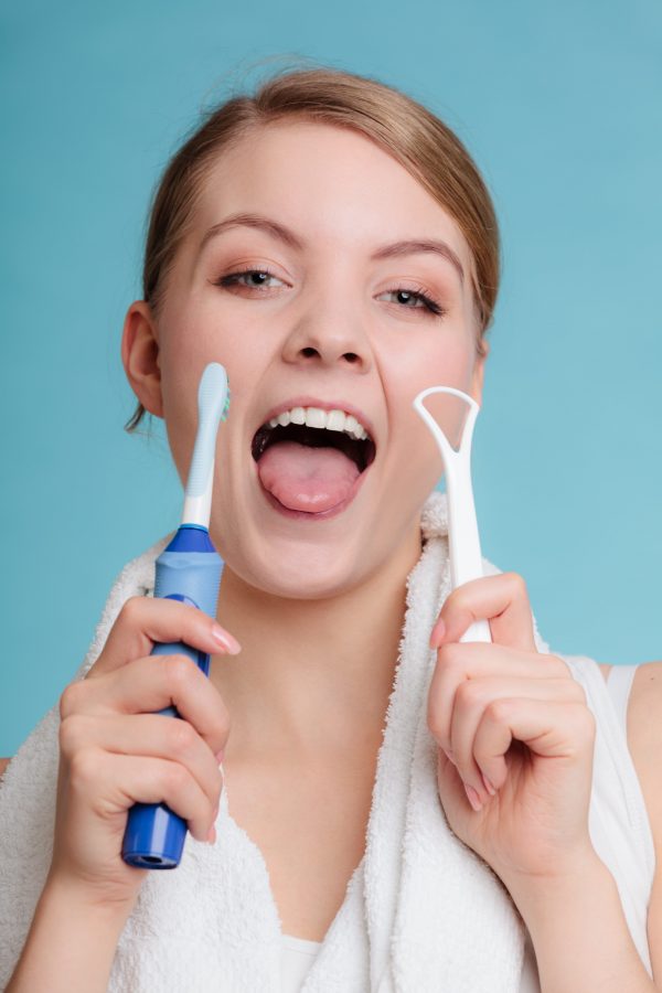 Young girl with electric brush and tongue scraper